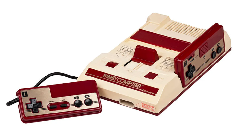 Image of the Nintendo Family Computer console, featuring a red and beige design, with one controller connected.